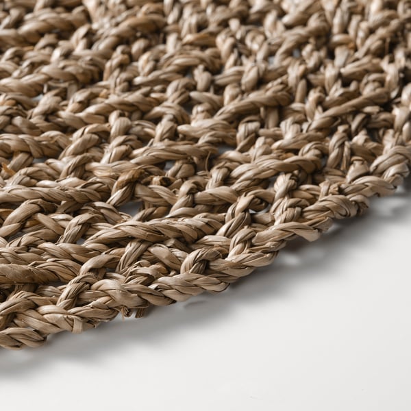 Close-up of intricately woven beige seagrass place mat, showcasing natural texture and quality.