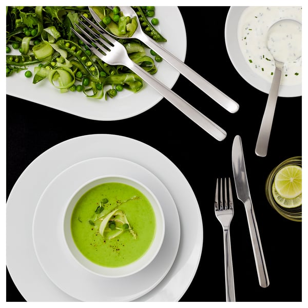 Image IKEA 365+ stainless steel cutlery with plates and green food. Modern, sleek design.