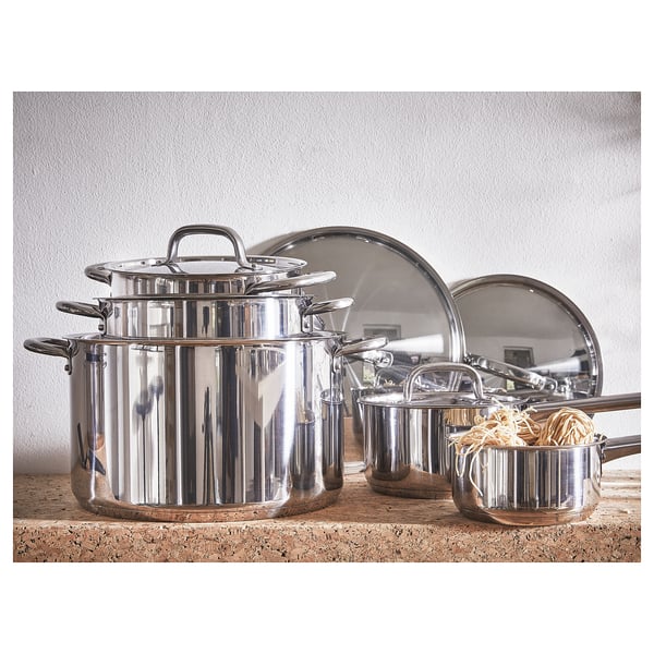Stainless steel IKEA 365+ cookware set; includes three pots with lids on distressed wooden shelf.