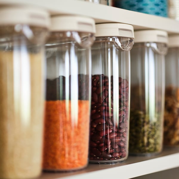 Shelf with transparent jars storing beans, rice, and herbs; part of IKEA 365+ series for food storage.