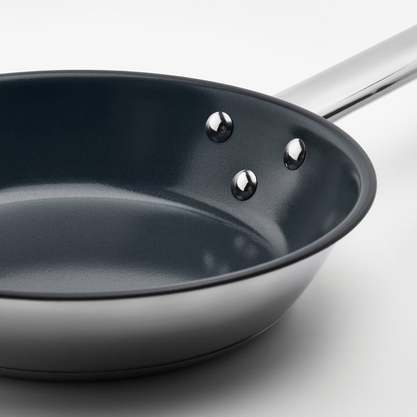 A high-quality ikea frying pan with a dark non-stick interior, a sturdy stainless steel handle, and three rivets securing the handle to the pan.