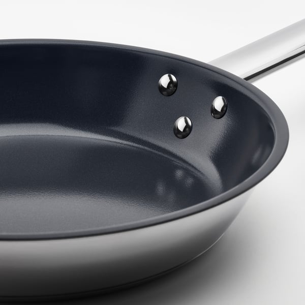 A high-quality stainless steel pan with a smooth, dark non-stick interior and durable riveted handle, designed for easy cooking and cleaning.