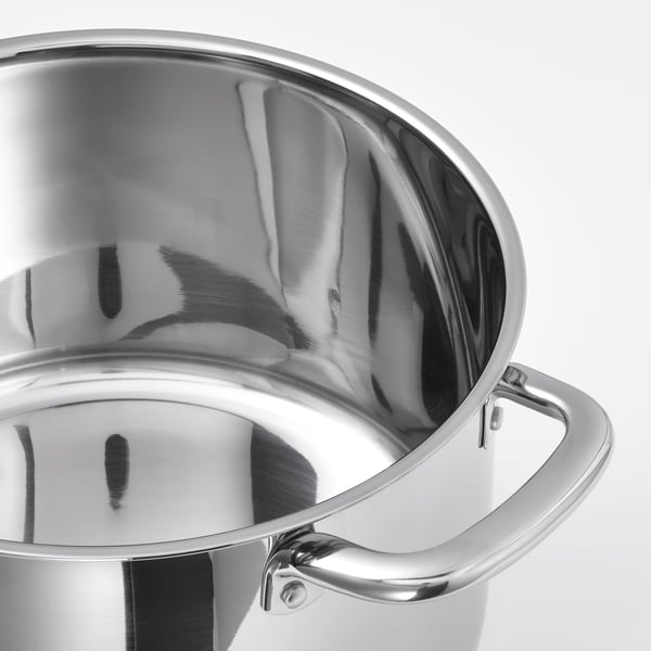 Polished stainless steel saucepan with large handle and curved interior, reflecting light.