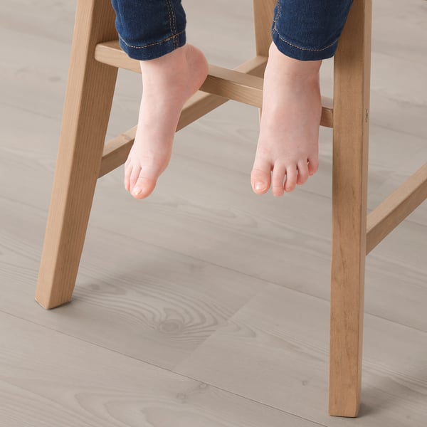 Childs feet in jeans dangling from wooden junior chair, providing comfortable support.