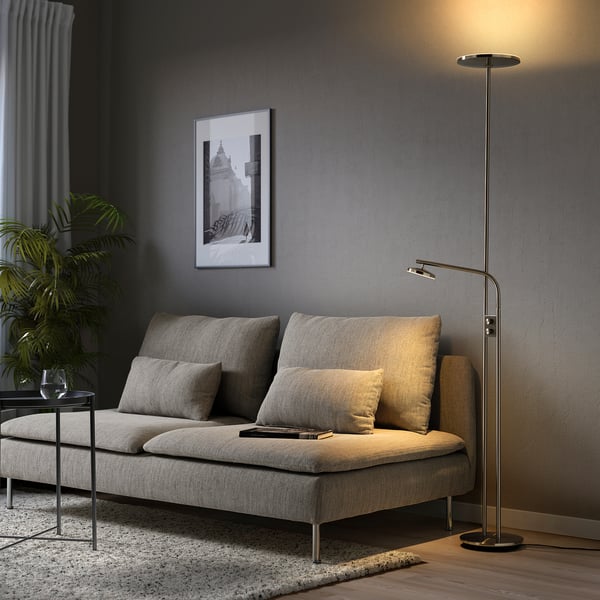 Grey floor lamp with dual lights beside cosy sofa & plant.