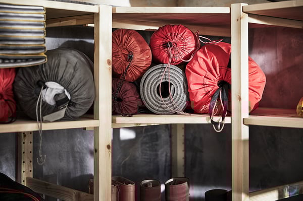 IVAR wooden shelves stock red bags, coiled rope, grey sandbags, black boots.
