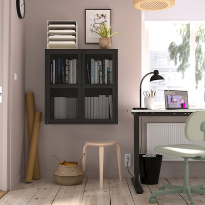 Black IVAR shelf with books on purple wall. Stool, basket. Desk with laptop, lamp, chair. Clock, art, window.