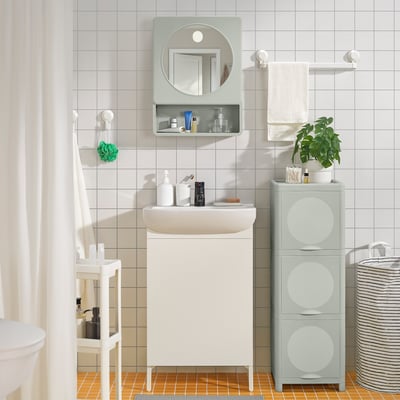 Modern bathroom with IVÖSJÖN white vanity; mirror, green shelves, clean lines.