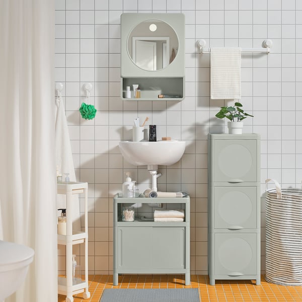 Small light grey IVÖSJÖN bathroom setup with rounded sink, limited shelving, and sliding doors fitting neatly under a compact round mirror.