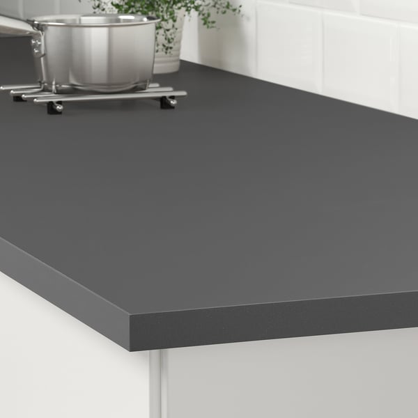 Black countertop with rounded edges. Stainless pots and plant. Easy to clean.