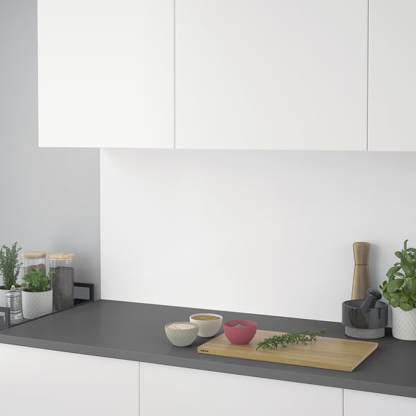 Modern kitchen counter with cutting board, bowls, herbs, and plants. Laminate worktop is easy to clean and maintain.