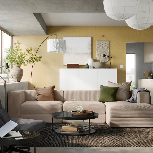 Modern living room with beige JÄTTEBO sectional sofa, mustard walls, and cosy decor.