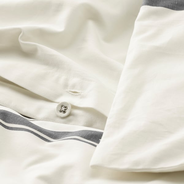 Close-up of crisp, white sheet with subtle grey stripes and a visible button.