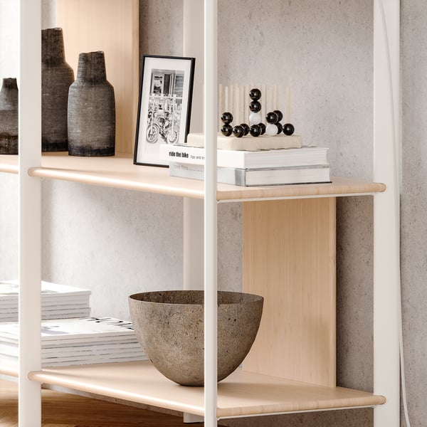 Modern white shelf with wooden slats, grey vase, black and white photo, stacks of books, and decorative spheres.