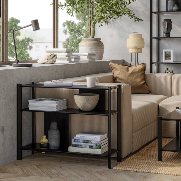 Small modern black and bamboo side table with shelves holding books, vases, and a bowl.