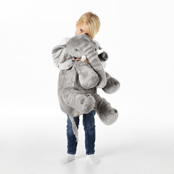 Child hugging large grey elephant cuddly toy, with floppy ears and white tusks, demonstrating its role as a comforting and cuddly companion.