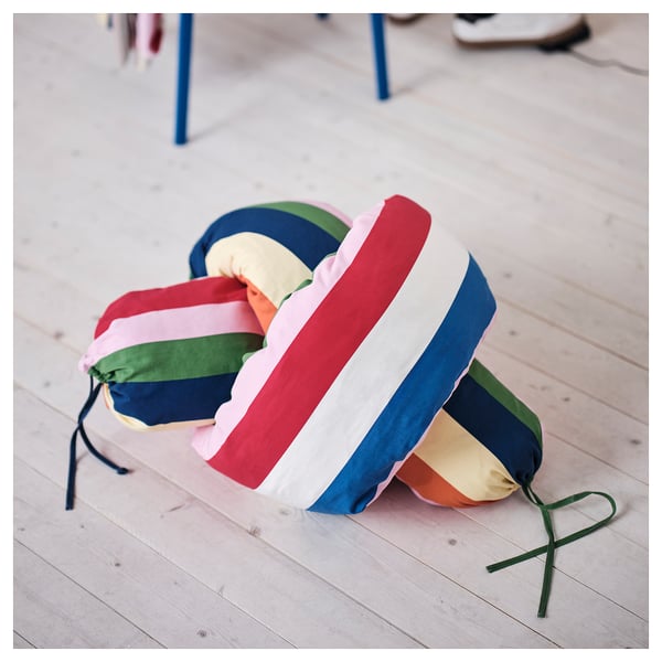 Bright cushions with multi-colored strips lie on a wooden floor, showcasing vibrant home décor creativity.