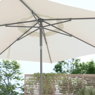 Describe JOGGESÖ beige patio umbrella with aluminium pole and steel ribs, tilted for shade.