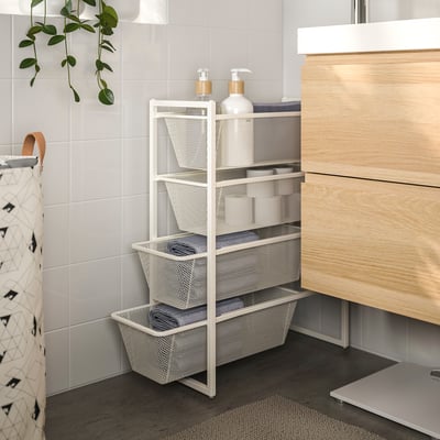 White JONAXEL storage rack with towels, bottles; between cabinet & wall, plant left