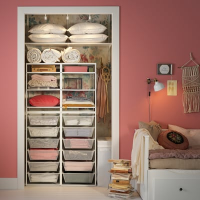 Well-organized closet with JONAXEL white metal shelves and mesh baskets, storing bed linens, clothes, and pillows in a pink room.