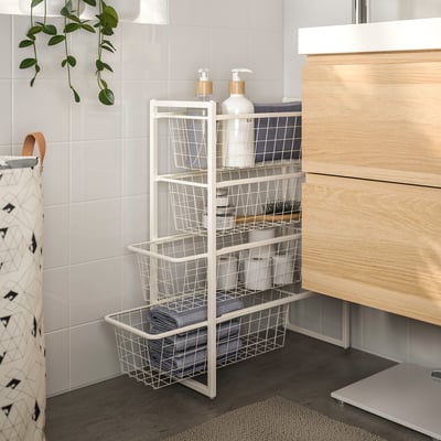 JONAXEL white metal bathroom storage unit with multiple baskets, neatly storing bottles and towels, situated between tiled wall and wooden vanity.
