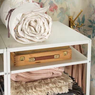 White JONAXEL storage unit with rolled comforter and wooden box.
