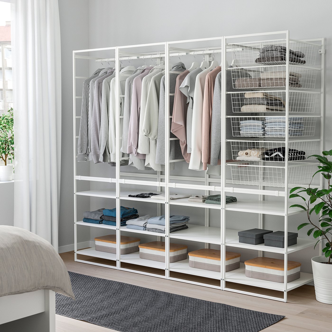 White metal wardrobe with shelves & hanging space, neatly organised beside a bed.