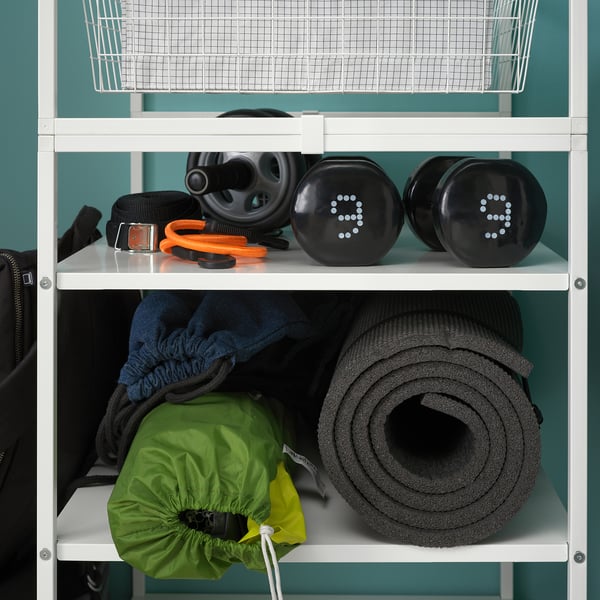 White JONAXEL shelving unit with black exercise equipment and grey yoga mat on teal wall.