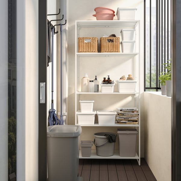 White JOSTEIN shelving unit with wicker baskets, plastic bins, and cleaning supplies, ideal for small spaces.