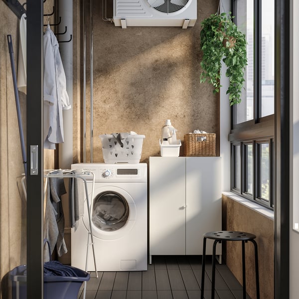 Laundry room with JOSTEIN cabinet, plants, clothes, and storage.