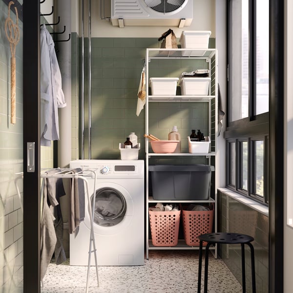 Laundry room with white JOSTEIN storage unit holding pink bins & cleaning items.