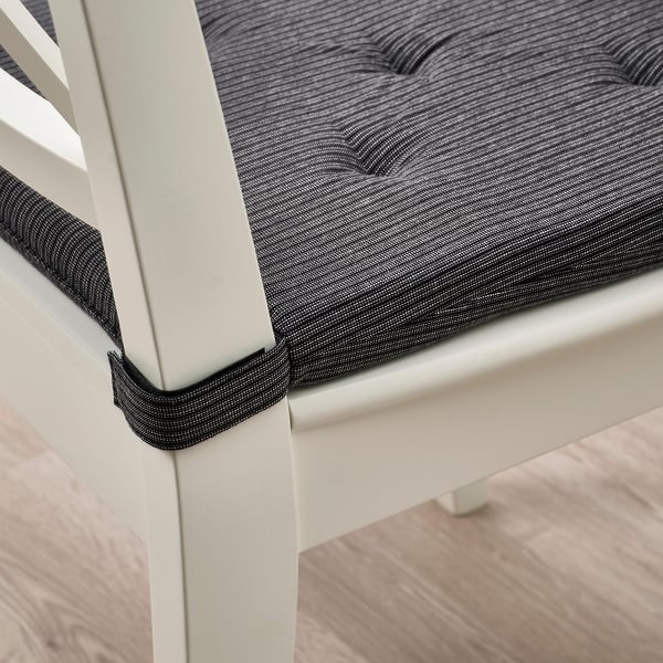 Close-up of JUSTINA chair pad, showing hook and loop fasteners securing it to a white chair.