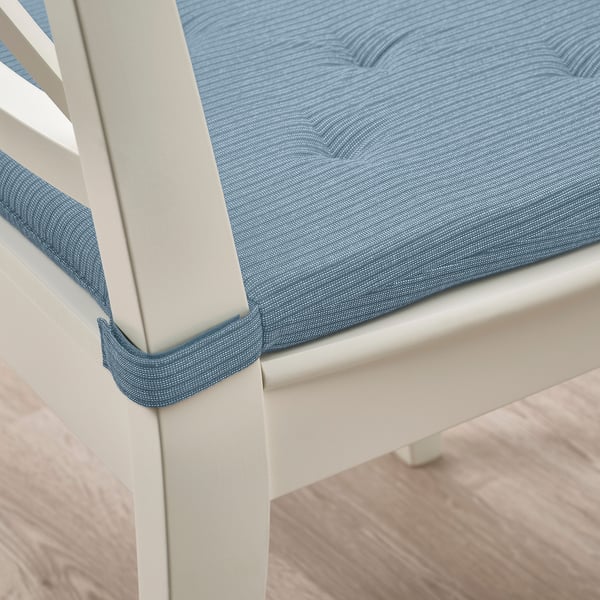 Close-up of a white chair with a blue cushion, attached with hooks and loops.