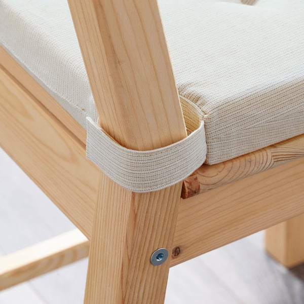 A wooden chair with a cream-colored cushion featuring hook-and-loop fasteners on its legs.