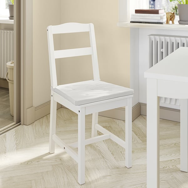 Depicts a white JUSTINA chair pad with a simple and comfortable design, featuring thick foam for support. It fastens to a chair with hooks and loops.