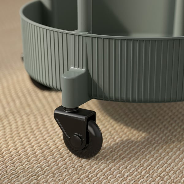 Green, rolling cart on floor. Durable plastic wheels, ribbed detailing. Modern, sturdy design.