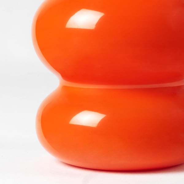 Bright orange glass vase, smoothly curved, reflective surface, part of IKEAs nytillverkad collection.