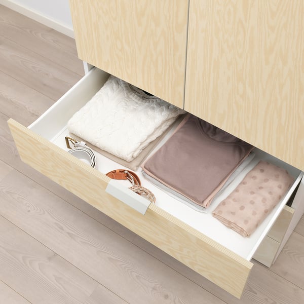 Open wooden drawer showing folded clothes, implying storage solution.