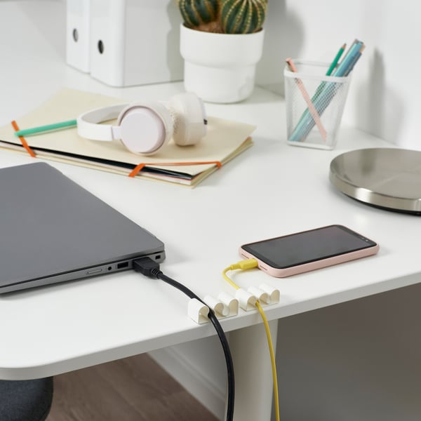 Image depicts a desk with a laptop, smartphone charging, and KALKSTUFF cable organisers keeping cords tidy.