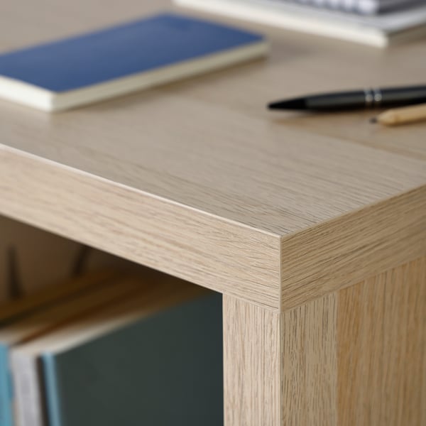 Wooden desk with visible grain texture, a black pen, and a blue notebook on its surface.