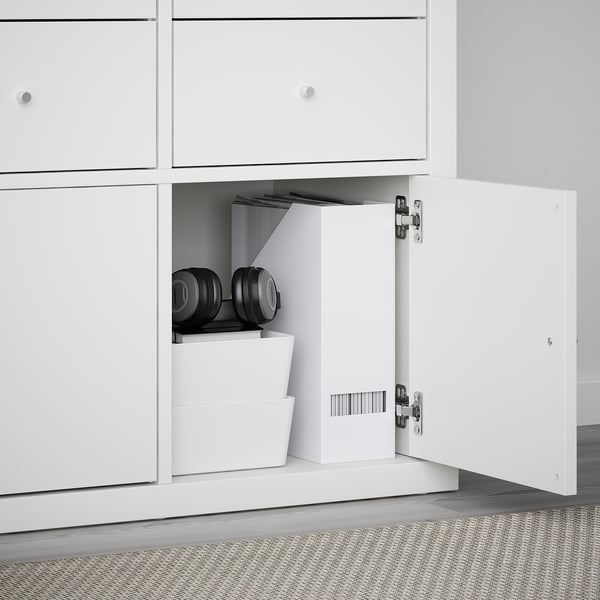 White cabinet with open door showing black dumbbells and storage boxes. Part of KALLAX series.
