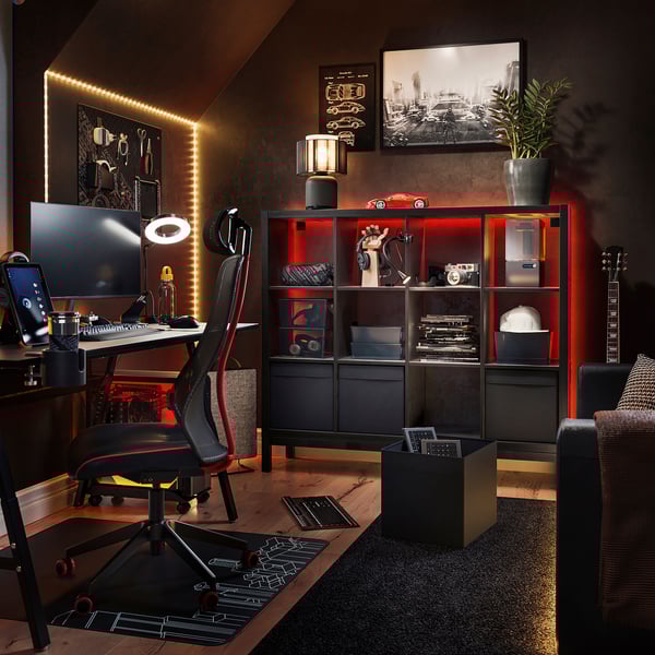 Modern home office with KALLAX black shelving, red lights, desktop pc, ergonomic chair, guitar, and decor.