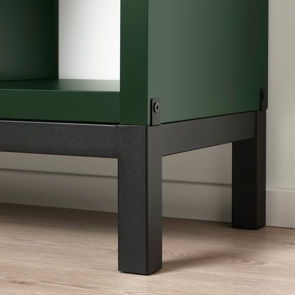 Closeup of modern green KALLAX shelf, sturdy black base, adjustable feet.