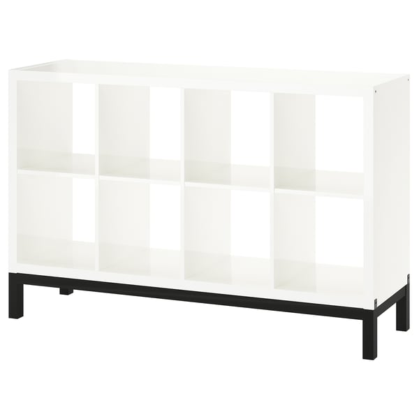 A KALLAX white bookshelf with a black metal base. It has a modern, minimalist design with multiple open shelves.