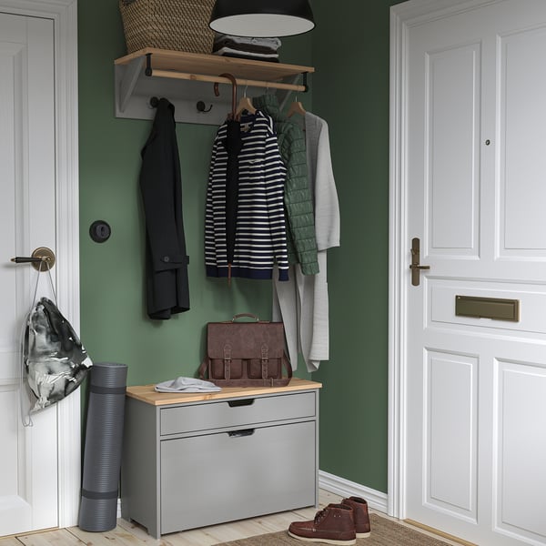 Grey & wood coat rack with hooks & bench, positioned between doors in a green corridor.