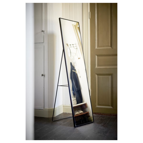 Black full-length mirror, KARMSUND, leaning, modern design with hooks, reflects room with doors.