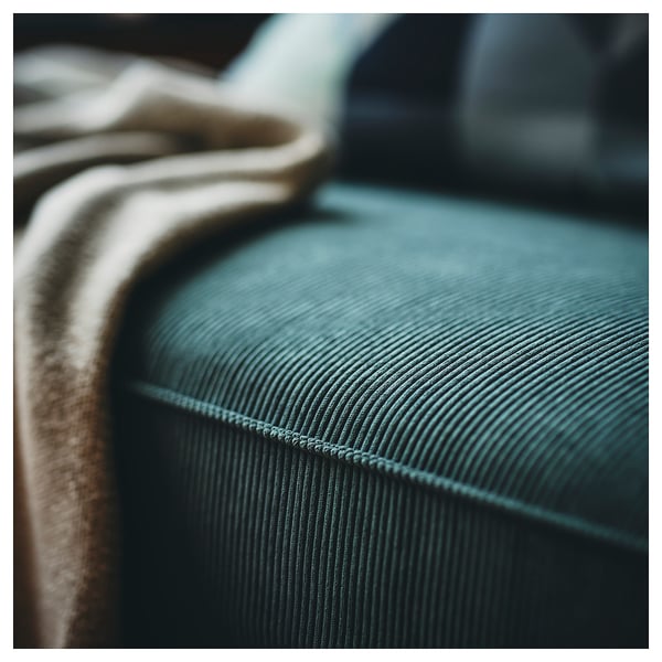 Close-up of teal KIVIK sofas plush, ribbed textile. Soft, comfy design.