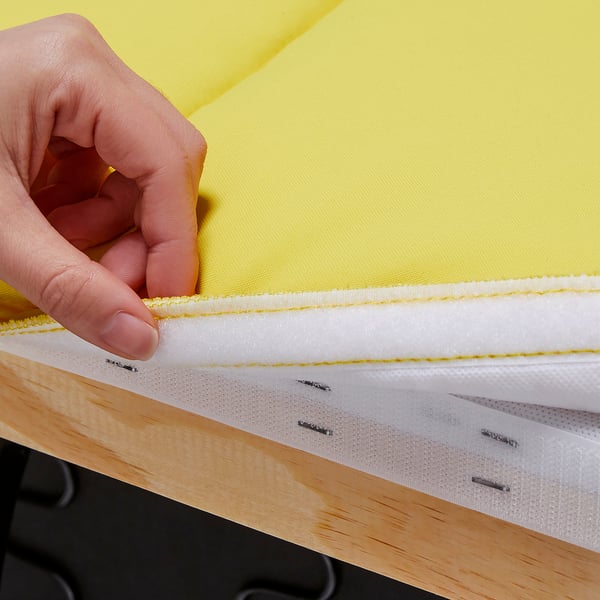 A hand holds a bright yellow sofa cushion, showing quality stitching and velcro fastening.