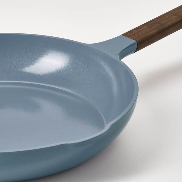 Modern, light blue skillet with wooden handle and non-stick coating.