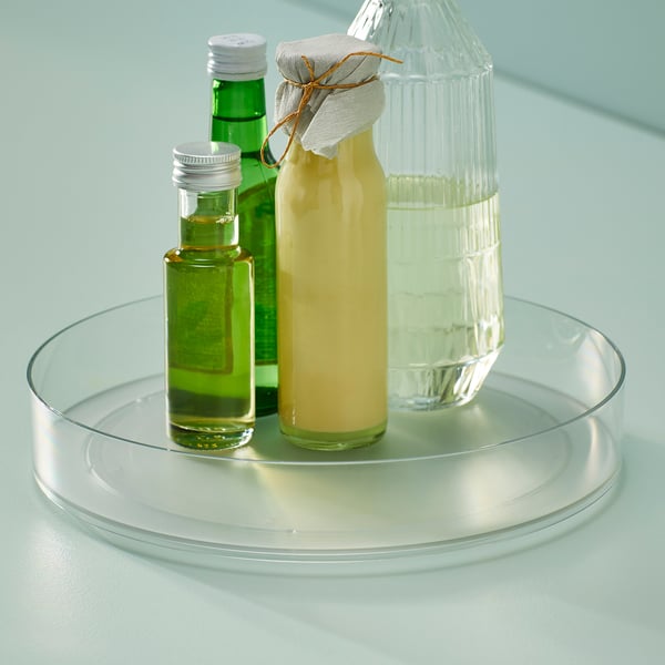 Glass turntable with three bottles: oil, juice, and water. Used for organised kitchen storage and access.